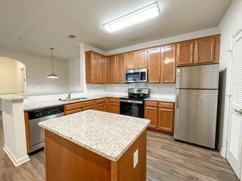 an empty kitchen with wooden cabinets and stainless steel appliances at The Crest at Sugarloaf, Lawrenceville, 30044